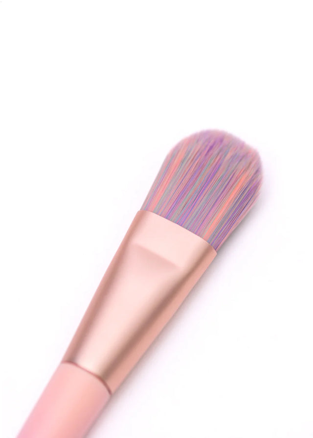 Close-up of a pastel-colored Unicorn Bronzer Brush with a rose gold ferrule and soft bristles on a white background