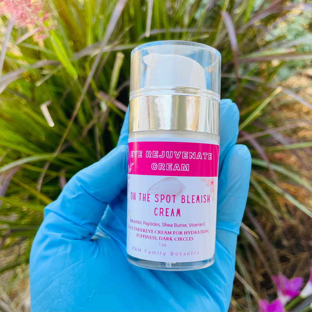 Hand wearing blue glove holding a bottle of Undereye Rejuvenate Cream against greenery background outdoors