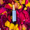 Wildflower No.2 perfume oil rollerball surrounded by vibrant red, yellow, and purple dried flower petals.